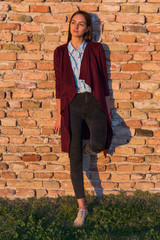 a beautiful girl poses in front of a medieval fortress at sunset