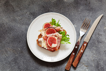 Sandwich with ham, ricotta cheese and figs on white plate
