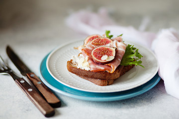 Sandwich with ham, ricotta cheese and figs on white plate