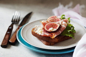 Sandwich with ham, ricotta cheese and figs on white plate