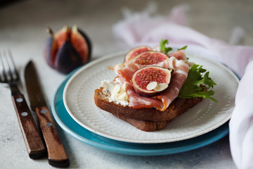 Sandwich with ham, ricotta cheese and figs on white plate