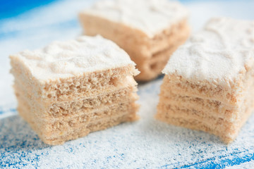 Pastila pieces on the blue wooden background covered with powdered sugar, side view