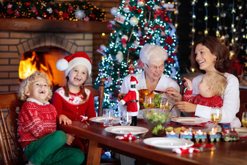 Christmas dinner. Family with kids at Xmas tree.