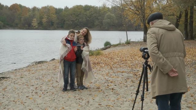 Gray-haired operator shoots a film in autumn park with family