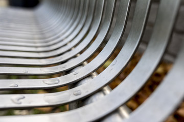 Close up of contemporary modern stainless steel street or park bench with water droplets that makes an interesting abstract background or architectural feature