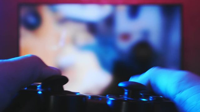 Close view of a gamer's hands playing shooter on his game console using joystick