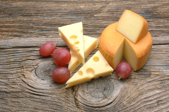 Cheese and grapes. Isolated on wooden table