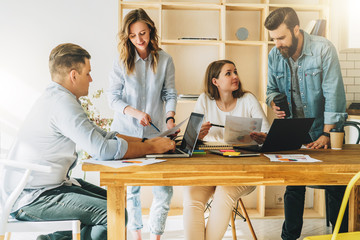 Teamwork, brainstorm. Group of young businesspeople work together in office at table, reading paper...