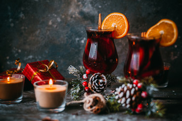 christmas hot mulled wine with spices, candle and traditional New Year decorations and orange on...