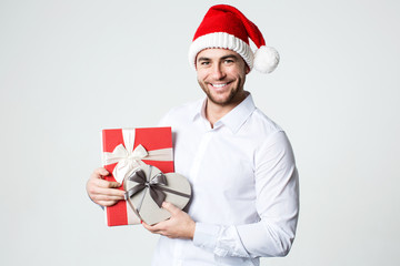 Attractive smiling man in Santa hat with gift boxes.