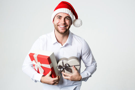 Attractive smiling man in Santa hat with gift boxes.