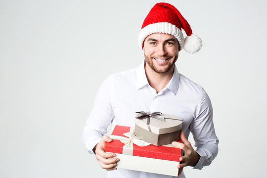 Smiling man in Santa hat with gift boxes.