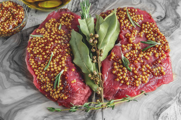 Cuts of beef for grilling on a cutting Board olive wood with pickled Dijon mustard, rosemary and herbs de Provence in a rustic style.