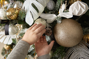 The child adjusts the toy on the tree with his hands