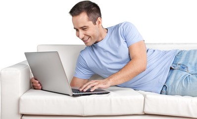 Smiling Man Using Laptop while Lying on a Couch