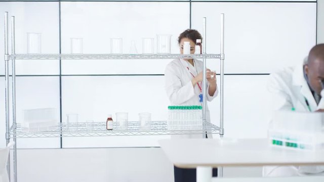  Medical researchers in white coats working in lab & discussing analysis