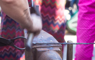 blacksmith performs the forging of hot glowing metal on the anvil