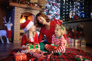 Fototapeta na wymiar Family with kids at Christmas tree and fireplace.
