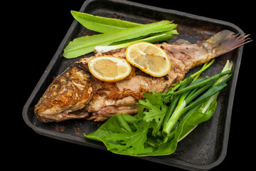 Baked carp marinated in lemon and spices with green leaf lettuce . Isolated.
