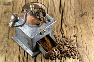 vintage coffee grinder with manufacture roasted Indonesian Arabica coffee beans on rustic wooden background