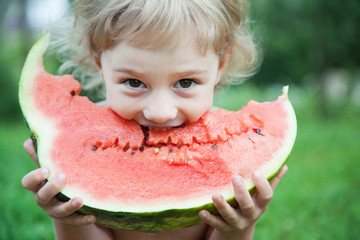Funny little girl eating big slice of watermelon
