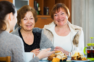 Senior women talking with girl while tea drinking