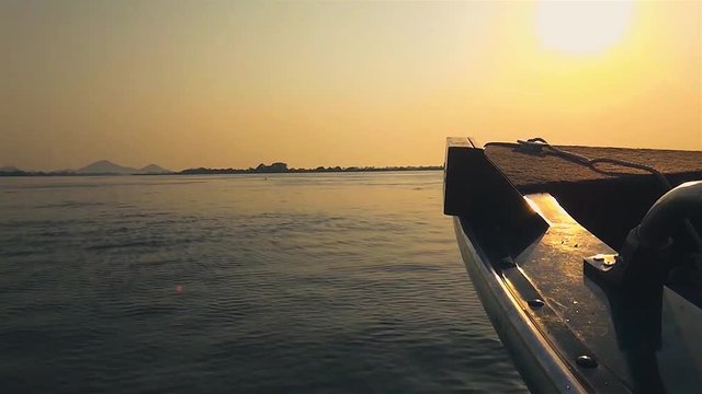 Boat navigating on Pantanal waters. The front of the boat surrounded by water and nature. Photo at golden hour with a amazing colorful landscape in Pantanal, Brazil.