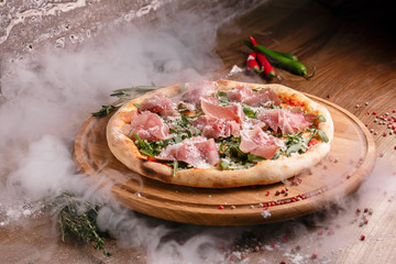 Delicious spanish pizza with cherry tomato and jamon italian style on wooden plate
