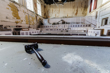 Judge's gavel lying on the bench of a derelict court room