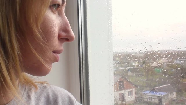 Girl looking out of window a rainy day