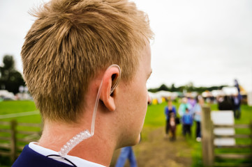 A young security guard wearing a coiled earpiece to listen to his two-way radio