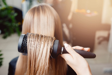 Stylist puts a hair dryer and comb hair in a hairdresser