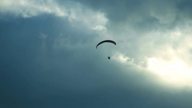 Paraglider flies in the clouds. Air sport and recreation. A powered paraglider - a glider with a dorsal power plant, providing the rise and moving in the air.