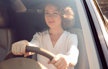 Young businesswoman driving a car, view from outside through windscreen