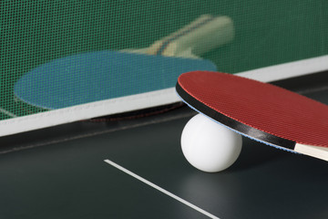Ping Pong Paddles on Table with Net, one out of focus
