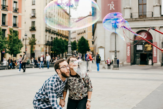 .A young couple in love walking around Madrid and enjoying a very fun day of sightseeing around the city center. Playing with giant soap bubbles. Lifestyle