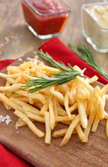 Yummy french fries on wooden kitchen board