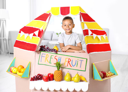 Cute little boy selling fruits at counter indoors