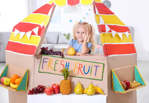 Cute little girl selling fruits at counter indoors