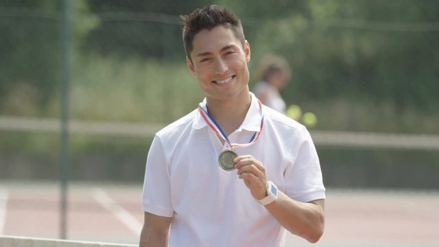  Portrait smiling tennis player with medal on outdoor court in the summer
