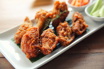 Buffalo wings barbecue chicken with carrots  and cucumbers on wood background
