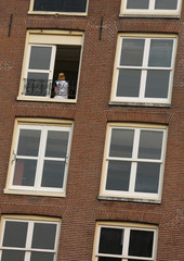 Fototapeta premium blonde girl at the apartment building window in an european city