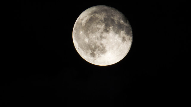 Bright Full-Moon phase with many craters and a little bit of water vapor in a dark sky.