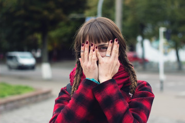 Fototapeta premium Young woman hides her face in her palms and spies