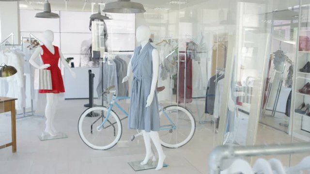 Interior of a fashionable women's clothing store with clothes racks and mannequins.