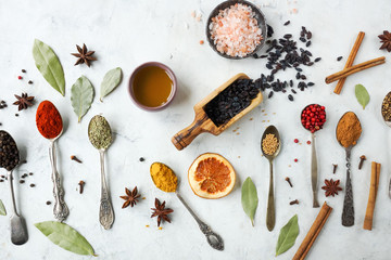 Various colorful indian spices and herbs in silver spoons on white background