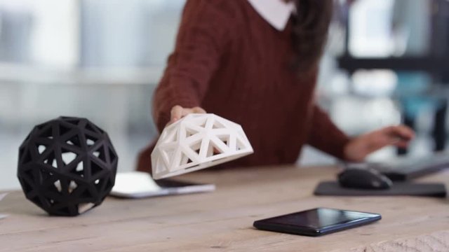  Designer working at her desk looking at 3D printed object. Technology & desig