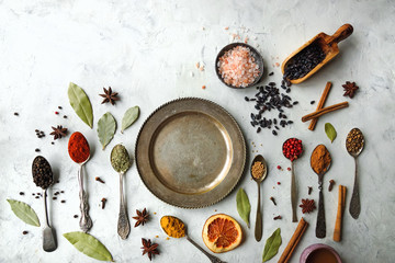 Various colorful indian spices and herbs in silver spoons on white background