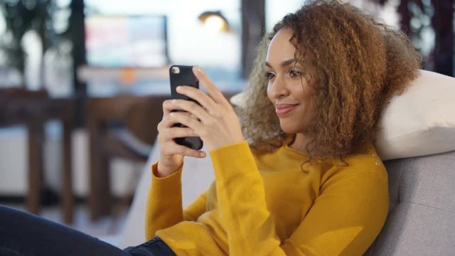  Portrait smiling woman relaxing at home & looking at smartphone