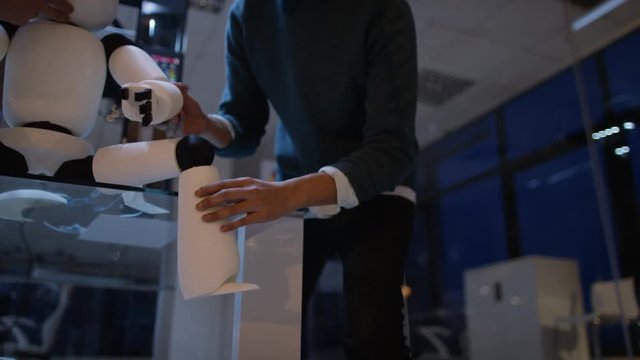 Electronics engineers testing automated robot with 3D printer in background